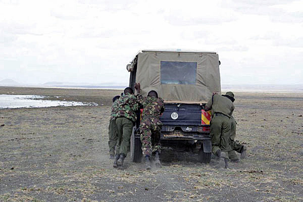 Policemen attached to North Horr push their vehicle after its engine failed to start as they were partolling at Crocodile bay at the Lake Turkana shores within Sibiloi National park on November 4, 2013. Security has been beefed up in and around the park as more tourists visit to enjoy heritage tourism and archeological sites. Photo/ JOSEPH KANYI