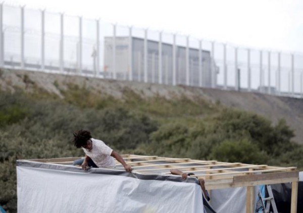 A migrant from Eritrea builds a shelter with wood and plastic sheets at "The New Jungle" camp in Calais, France, August 4, 2015. REUTERS/Peter Nicholls