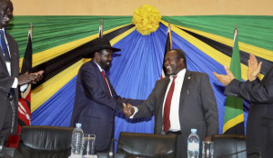 In this photo taken Wednesday, Jan. 21, 2015, South Sudan's President Salva Kiir, left, shakes hands with rebel leader and former vice president Riek Machar, right, after signing an agreement at the end of talks in Arusha, Tanzania. South Sudan's warring factions have agreed to reunify their political party, a conflict resolution organization said Thursday, with South Sudan President Salva Kiir and rebel leader Riek Machar signing the agreement to unite the ruling Sudan People's Liberation Movement on Wednesday in the Tanzanian town of Arusha, according to the Conflict Management Initiative. (AP Photo)