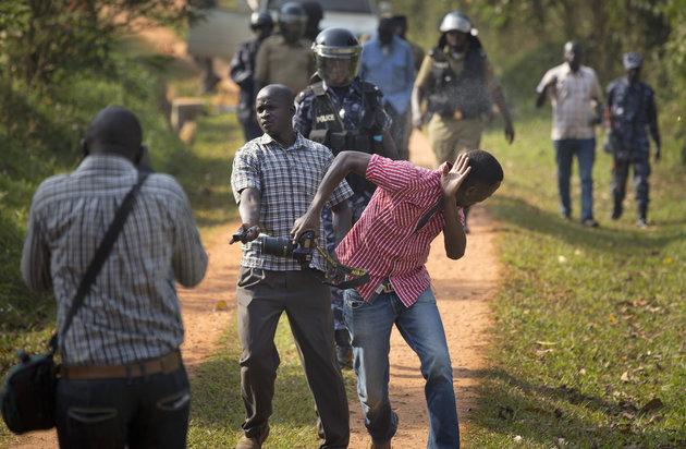 A plainclothes security agent sprays pepper into the face of a Ugandan photojournalist, as he was walking away after taking photographs of opposition leader Kizza Besigye attempting to leave his home, in Kasangati, Uganda Monday, Feb. 22, 2016. Besigye was arrested again Monday as he tried to leave his home, in which he had already been placed under house arrest, as he attempted to visit the election commission's headquarters in Kampala to get detailed copies of the results from the country's presidential election. (AP Photo/Ben Curtis)