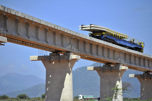 A rail wagon carries sections of railway sleepers and tracks towards the bridge end during the construction of a superbridge which will form part of the new Mombasa-Nairobi Standard Gauge Railway (SGR) line, in Voi, Kenya, on Wednesday, March 16, 2016. By providing an alternative to roads, the 1,100-kilometer (684-mile) Chinese-financed railway will slash the time and cost of transporting people and goods between East Africa's landlocked nations. Photographer: Riccardo Gangale/Bloomberg