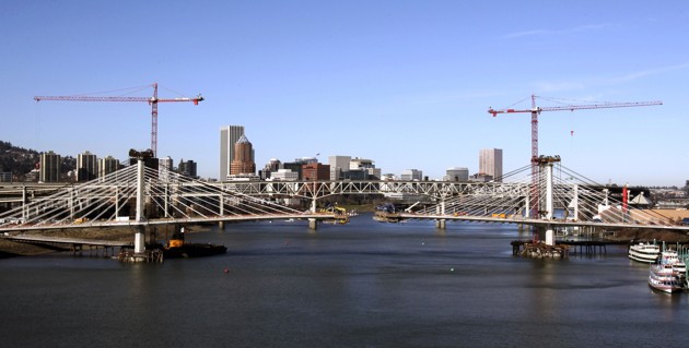Downtown Portland is framed by cranes and uprights of the Portland-Milwaukee light rail bridge, currently under construction, in Portland, Ore., Friday, Jan. 24, 2014. The bridge, due to open when light rail service begins in 2015, will serve light rail trains, pedestrians, cyclists and in the future, the Portland Streetcar. (AP Photo/Don Ryan)