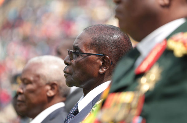 epa05467925 Zimbabwean President Robert Mugabe (C) stands as the national anthem was being sung at the National Sports Stadium in Harare, Zimbabwe, 09 August 2016. The Zimbabwe defence forces held their 36 th commemorations at the stadium and Zimbabwean President Robert Mugabe addressed thousands of people who gathered. EPA/AARON UFUMELI